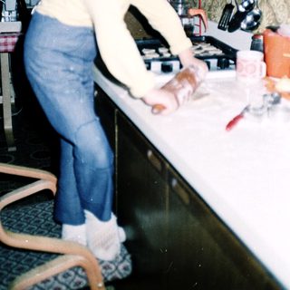 Young girl cutting food at kitchen counter.