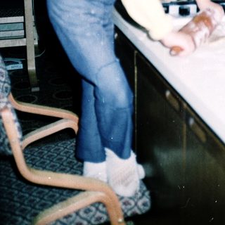 Young girl cutting food at kitchen counter.