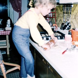 Young girl cutting food at kitchen counter.