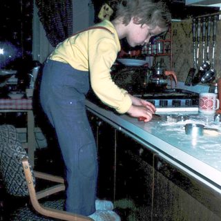 Child cooking at kitchen counter with adult supervision.