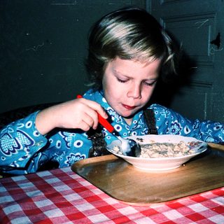 Child eating cereal with a spoon.