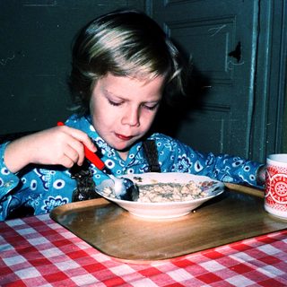 Child eating cereal with a spoon.