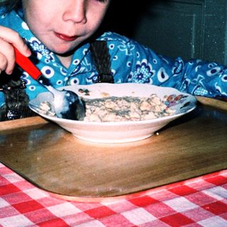 Child eating cereal with a spoon.