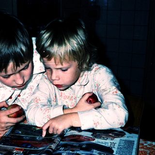 Two children intently reading a book together.