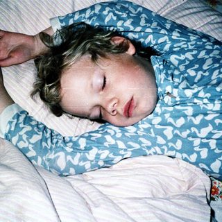 Child peacefully sleeping on patterned bedding.