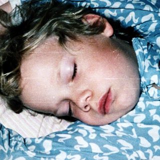 Child peacefully sleeping on patterned bedding.