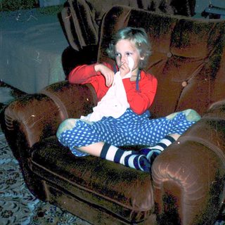 Child sitting on armchair eating snack.