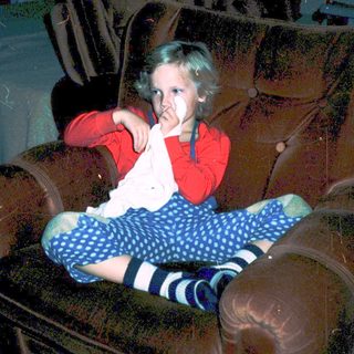 Child sitting on armchair eating snack.