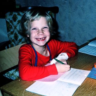 Young child happily writing at a desk.
