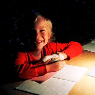 Child happily drawing with colored pencils.
