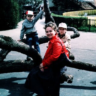 Family posing on fallen tree trunk outdoors.