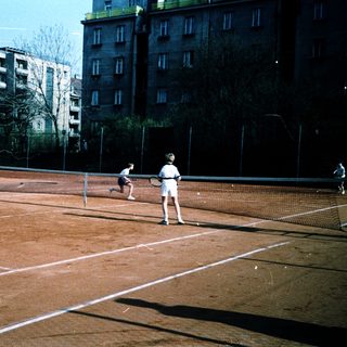 People playing tennis on outdoor clay court.