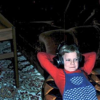 Child relaxing with headphones on indoors.