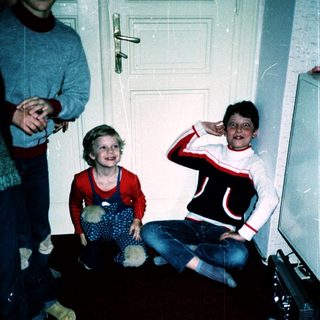 Three children posing indoors near a door.