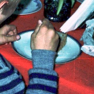 Children gathered around a table eating cake.
