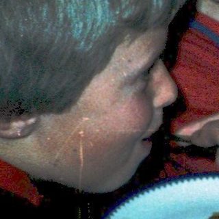 Children gathered around a table eating cake.