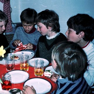 Group of children gathered around a table eating.