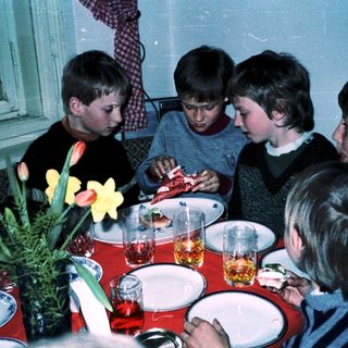 Group of children gathered around a table eating.