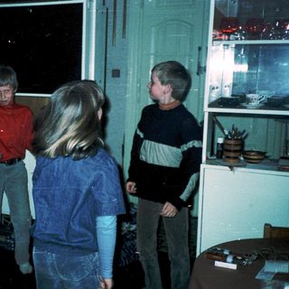 Four children playing indoors near a window.