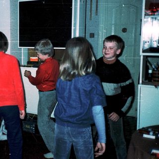 Five children playing video game together indoors.