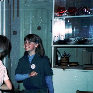Four children playing indoors in a dimly lit room.