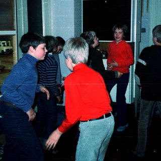 Group playing video game in dimly lit arcade.