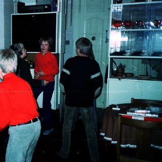 Group playing video game in dimly lit arcade.