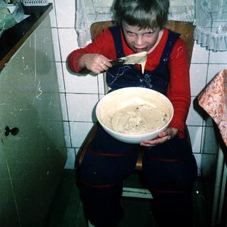 Child mixing batter in a bowl indoors.