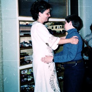 Woman hugging young boy in train station.