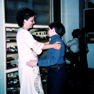 Woman hugging young boy in train station.