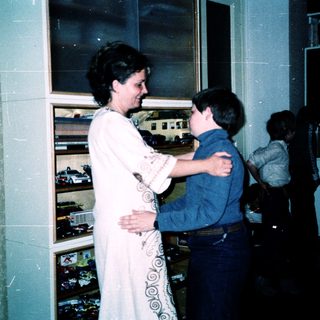Woman hugging young boy in train station.
