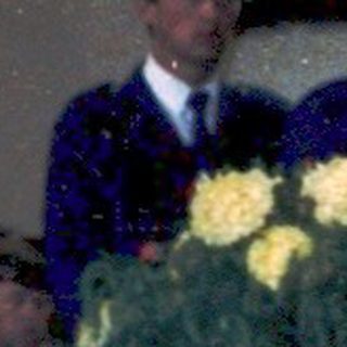 Funeral service with casket draped in flowers.
