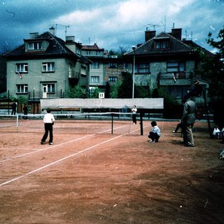 People playing tennis on outdoor clay court.