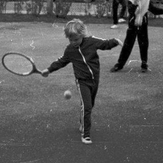 Two people playing tennis on outdoor court.