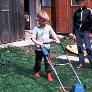 Family mowing lawn together outdoors.