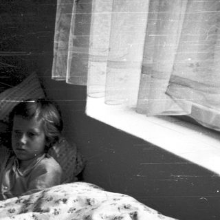 Two children sitting in bed together at night.