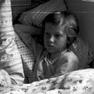 Two children sitting in bed together at night.