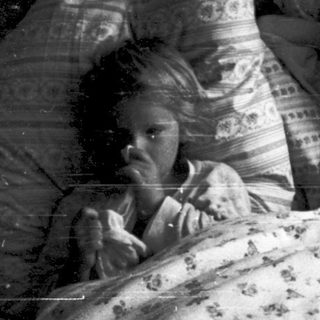 Two children sitting in bed together at night.