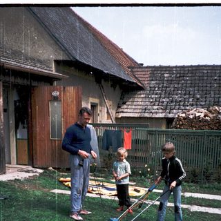 Family mowing lawn together outdoors in rain.