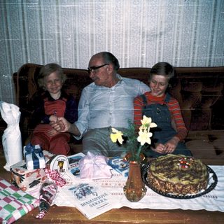 Family celebrating birthday with gifts and cake.