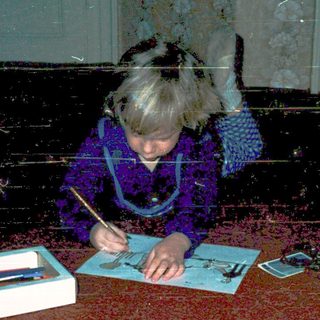 Child drawing with paintbrush on paper.