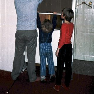 Family installing large glass door panel together.