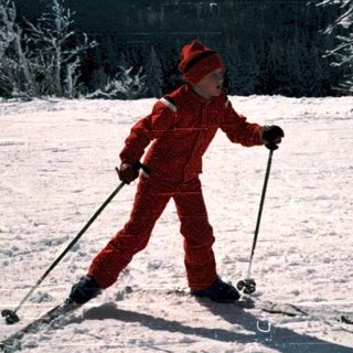Child cross-country skiing on snow-covered trail.