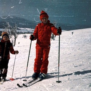 Two children skiing on snowy mountain slope.