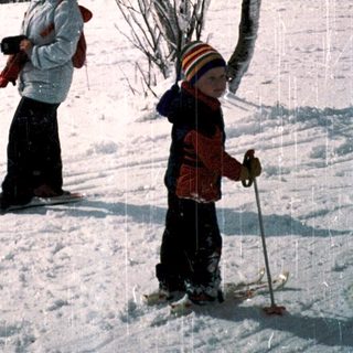 Two people cross-country skiing in snowy landscape.