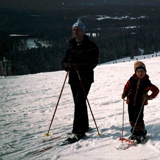 Two people cross-country skiing on snow-covered terrain.