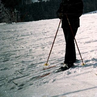 Two people cross-country skiing on snow-covered terrain.