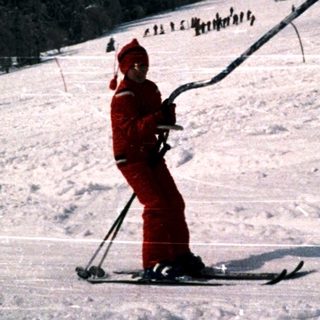 Skiier descending snowy slope at night.