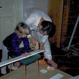 Children helping repair flooded floor with wooden planks.
