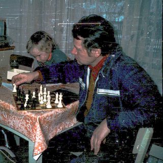 Three people playing chess indoors.